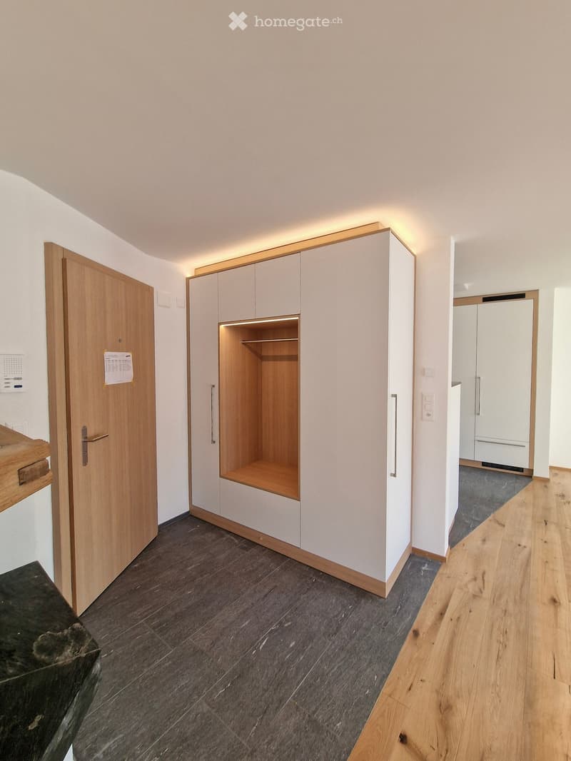 Empty hallway with wooden doors, built-in closet, and light wood flooring. No furniture or personal items visible.