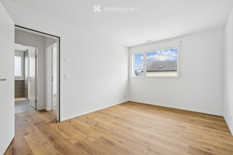 Empty room with white walls, wooden floor, glass window, and open door leading to another room.