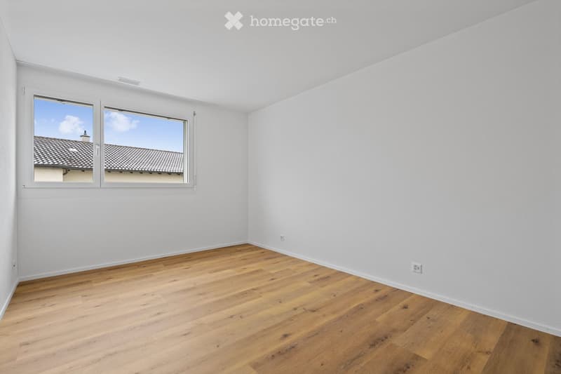 Empty room with white walls, wooden floor, double windows facing the outside, no furniture