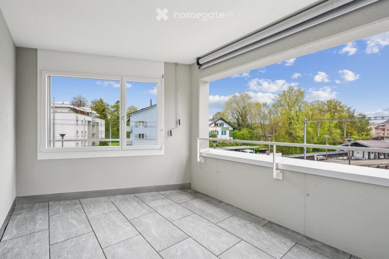 Balcony with floor tiles, white walls, two windows with view to outside