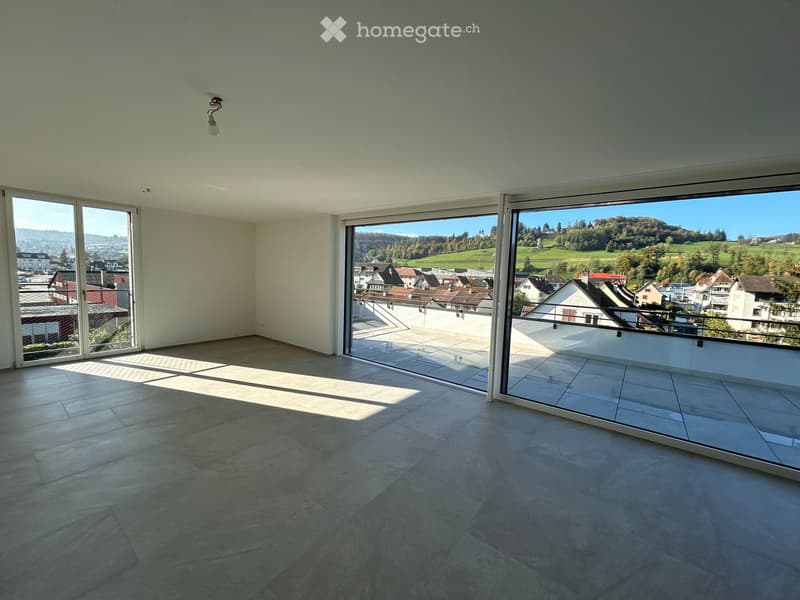 Empty room with sliding doors leading to a balcony, large windows, tiled floor, lamp hanging from ceiling.