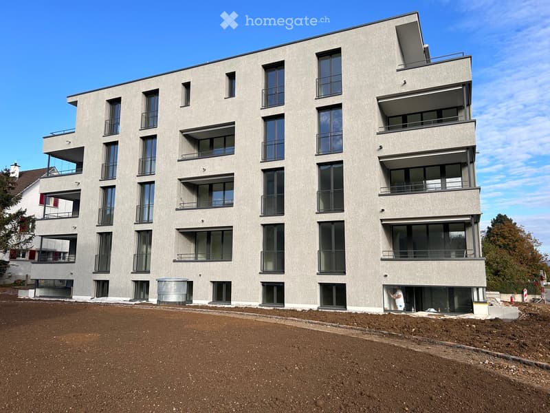 Modern apartment building, multiple floors, balconies, large windows, gray exterior, concrete base