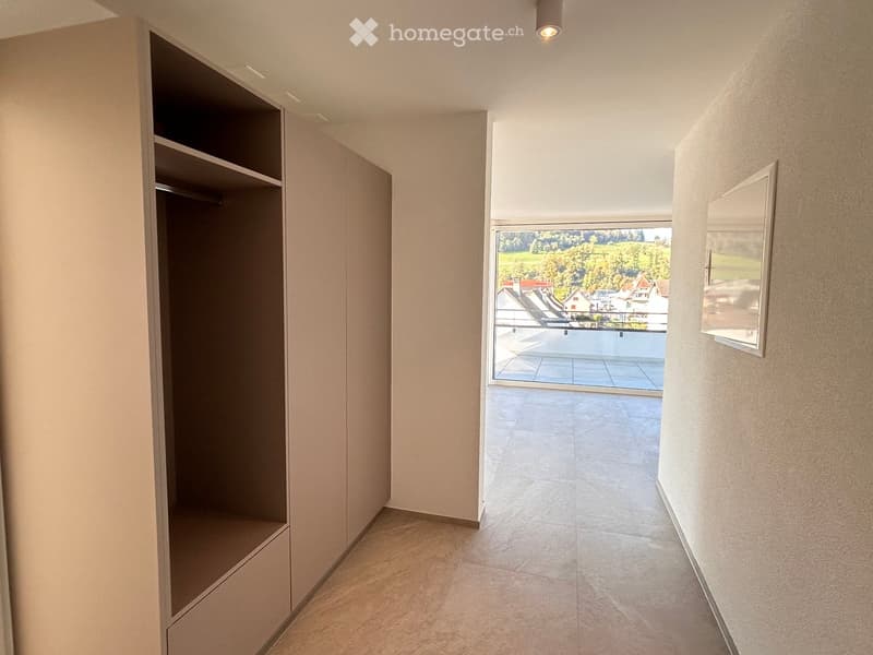 walk-in closet with hanging rails, adjacent to balcony with large windows, tiled floor