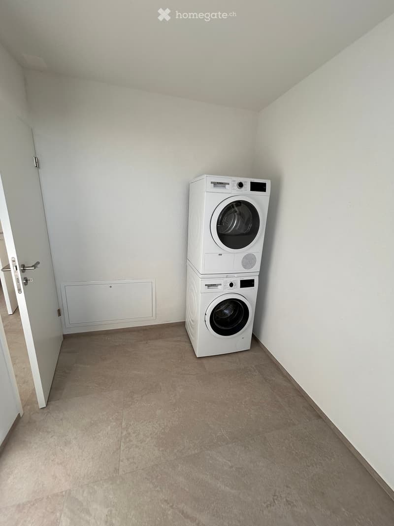 empty laundry room, white front load washer and dryer, open door, beige floor