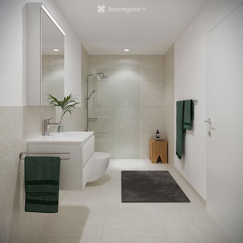 Modern bathroom with a white sink, toilet, shower, mirror, and a small wooden stool holding a bottle. Green towels are hanging on both sides of the sink.