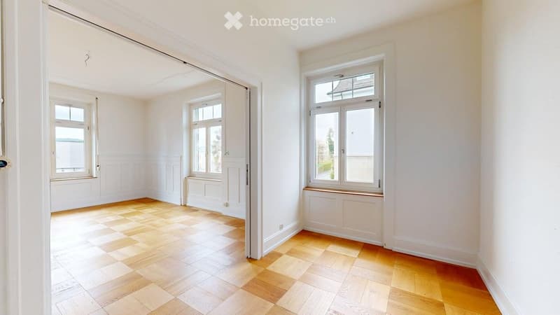 Empty room with wooden flooring, white walls, and multiple windows allowing natural light. No furniture or equipment present.
