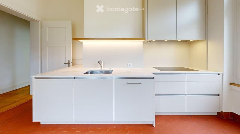 Modern kitchen with white cabinets, a central island, and a stainless steel sink.