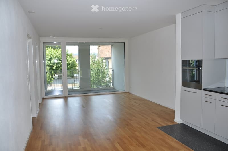 Bright, modern kitchen with white cabinets, a built-in oven, and a large sliding glass door leading to a balcony.
