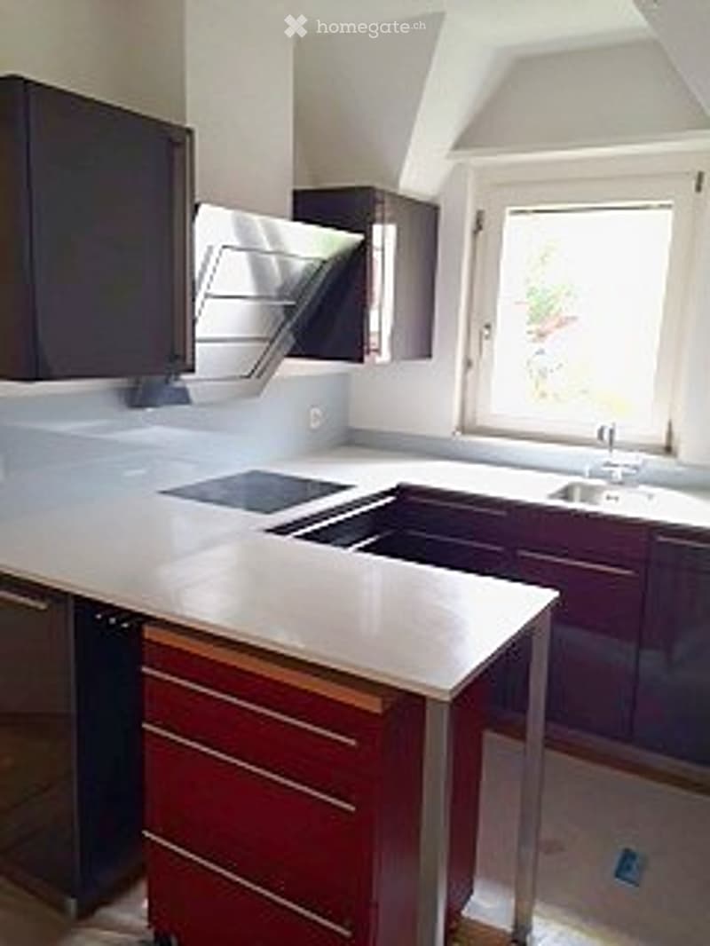 Modern kitchen with dark cabinets, white countertops, and stainless steel appliances including a stove and sink.