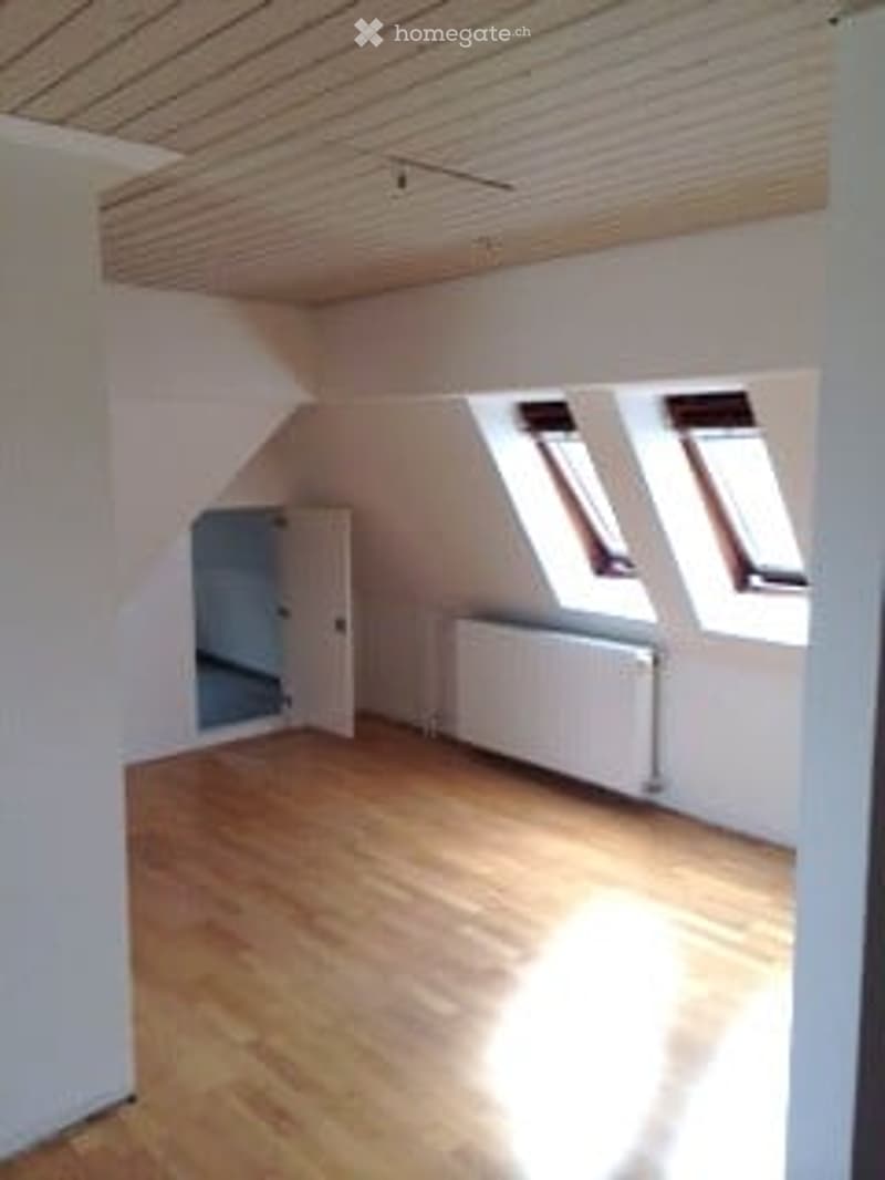 Empty room with wooden flooring, white walls, and skylight windows. No furniture or equipment present.