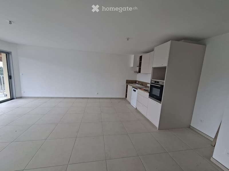 Empty kitchen with white cabinets, tiled floor, and a built-in oven. No furniture or appliances are present.