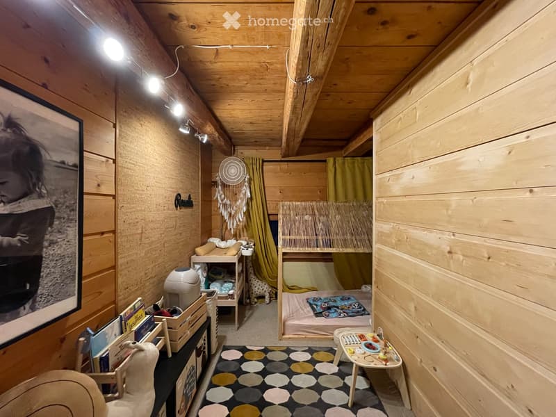 Cozy wooden bedroom with bunk bed, small table, chair, and decorative items.