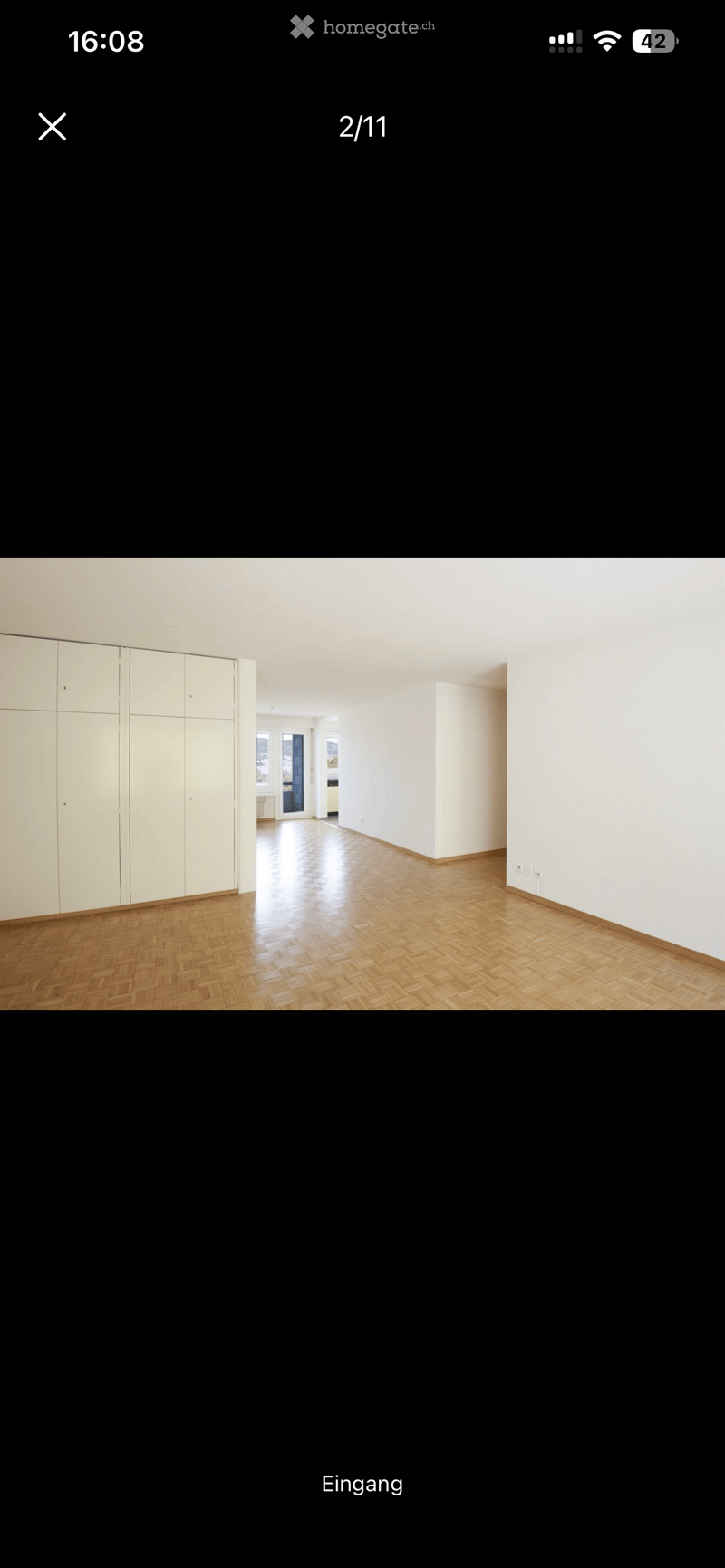 Empty room with wooden flooring, white walls, and a large built-in wardrobe on the left side.