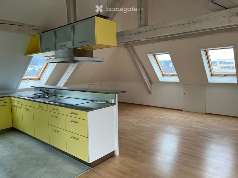 Modern kitchen with yellow and white cabinets, a central island with a black countertop, and multiple skylight windows allowing natural light.