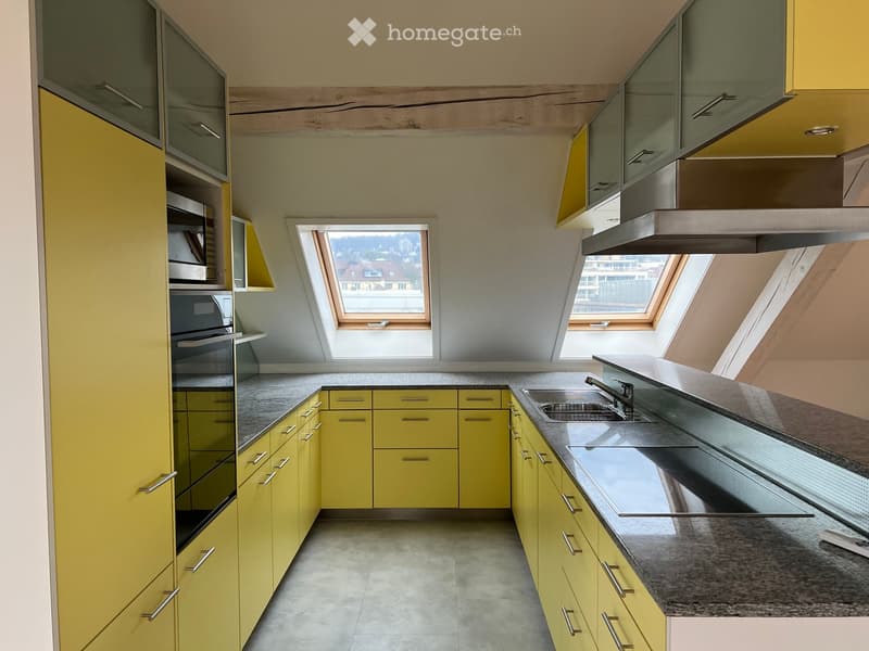 Bright kitchen with yellow cabinets, stainless steel appliances, and skylight windows offering a view of the city.