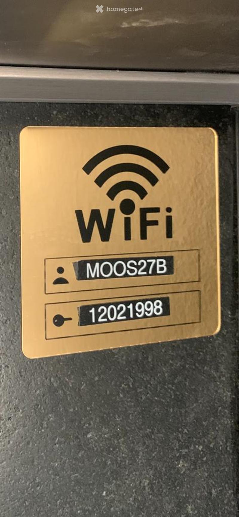 A gold-colored WiFi sign displaying the network name "MOOS27B" and password "12021998".