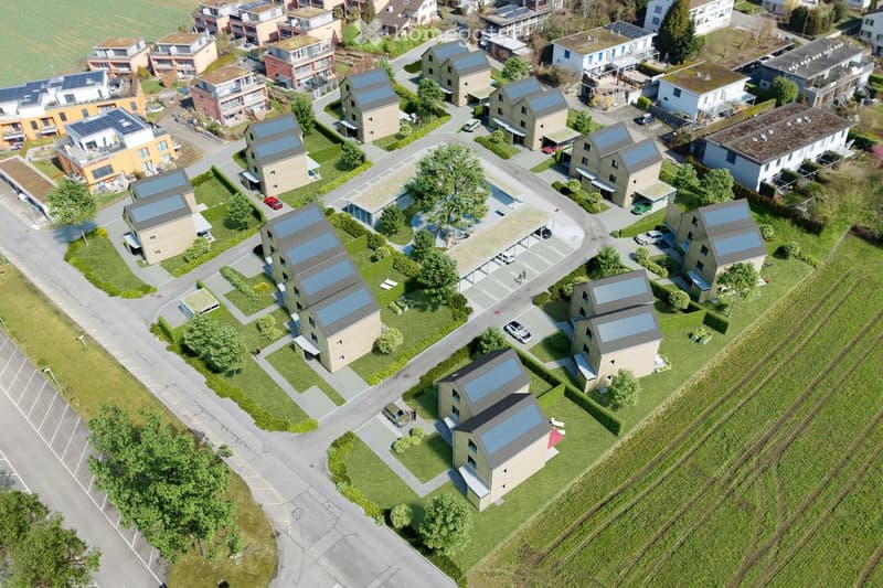 Aerial view of a residential neighborhood with multiple houses featuring solar panels on their roofs, surrounded by green spaces and parking areas.