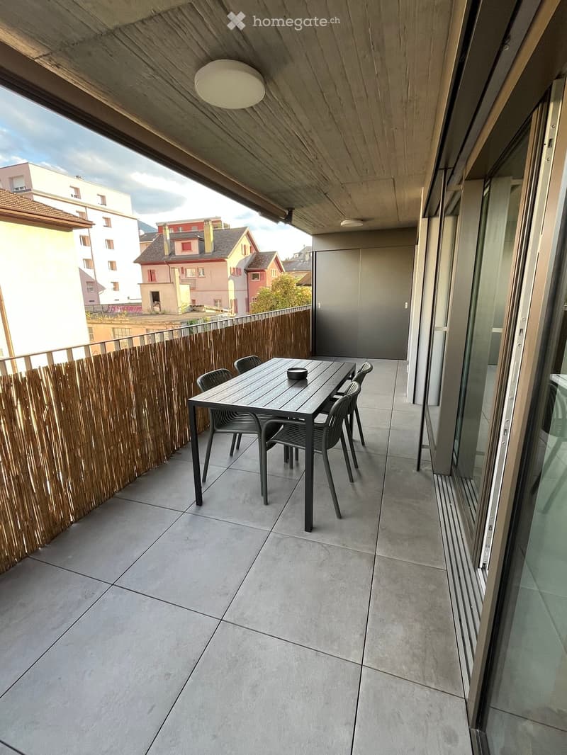 Balcony with tiled floor, wooden privacy screen, and a small table with chairs.