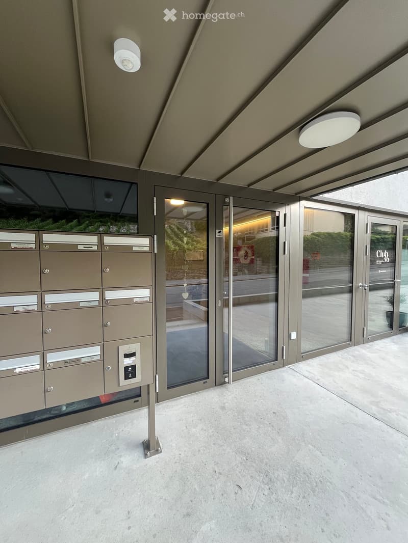 Modern entrance area with mailboxes, glass doors, and recessed lighting.