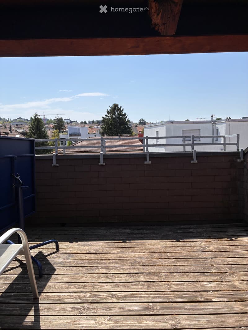 Wooden deck with railing, a single chair, and a view of the cityscape.