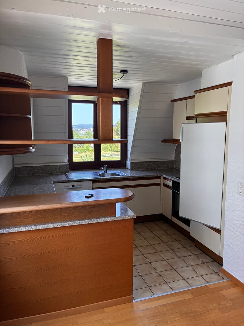 Modern kitchen with wooden cabinets, granite countertops, stainless steel sink, dishwasher, refrigerator, and oven. Features a large window with a scenic view.