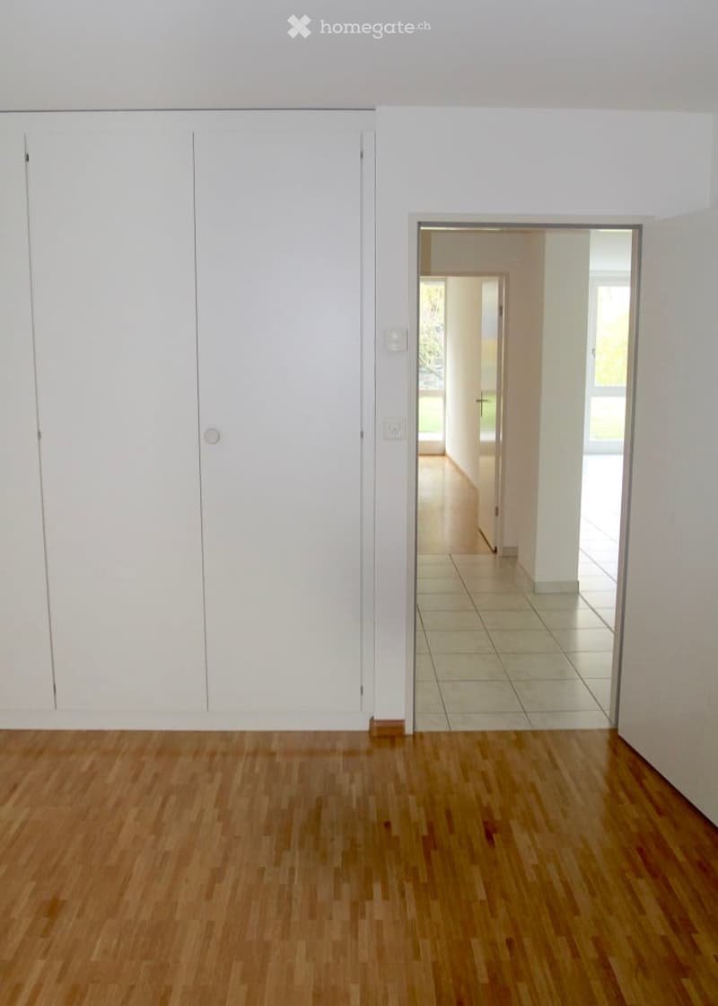 empty room, wooden floor, two closets, entrance with two doors, open door to hallway