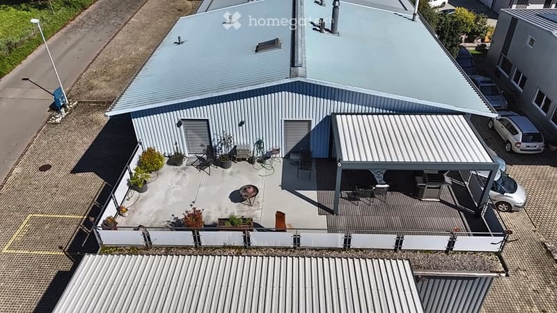 Roof terrace with a fire pit, chairs, a table, potted plants, and a covered parking area.