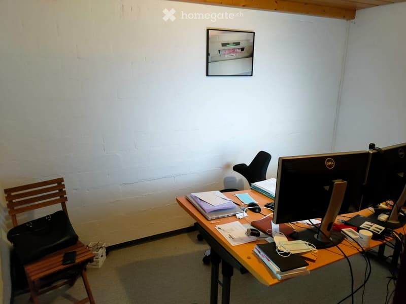 Office space with a wooden desk, two monitors, a laptop, a chair, and various office supplies.