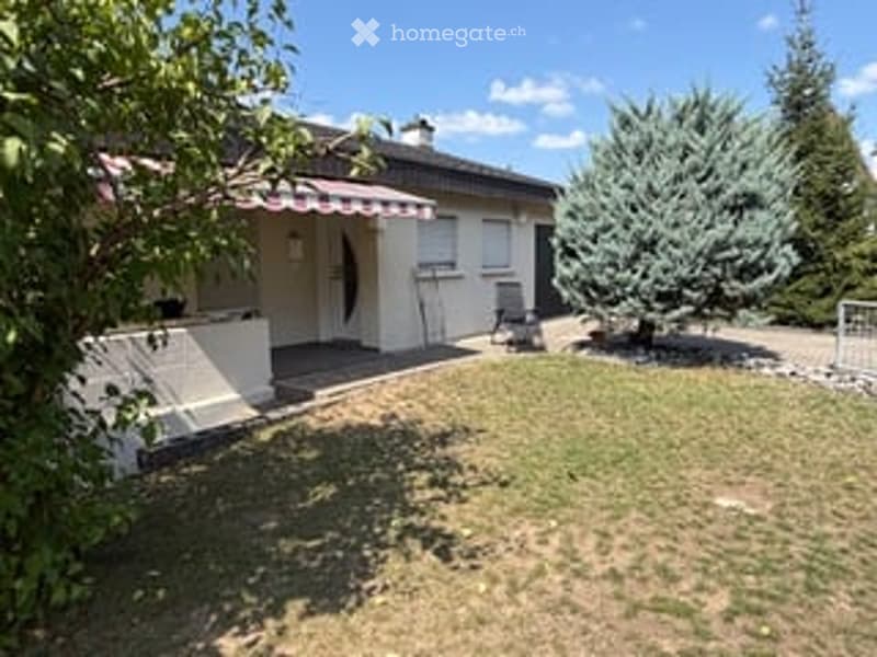 Single-story house with white exterior, red striped awning, small porch, and well-maintained lawn.