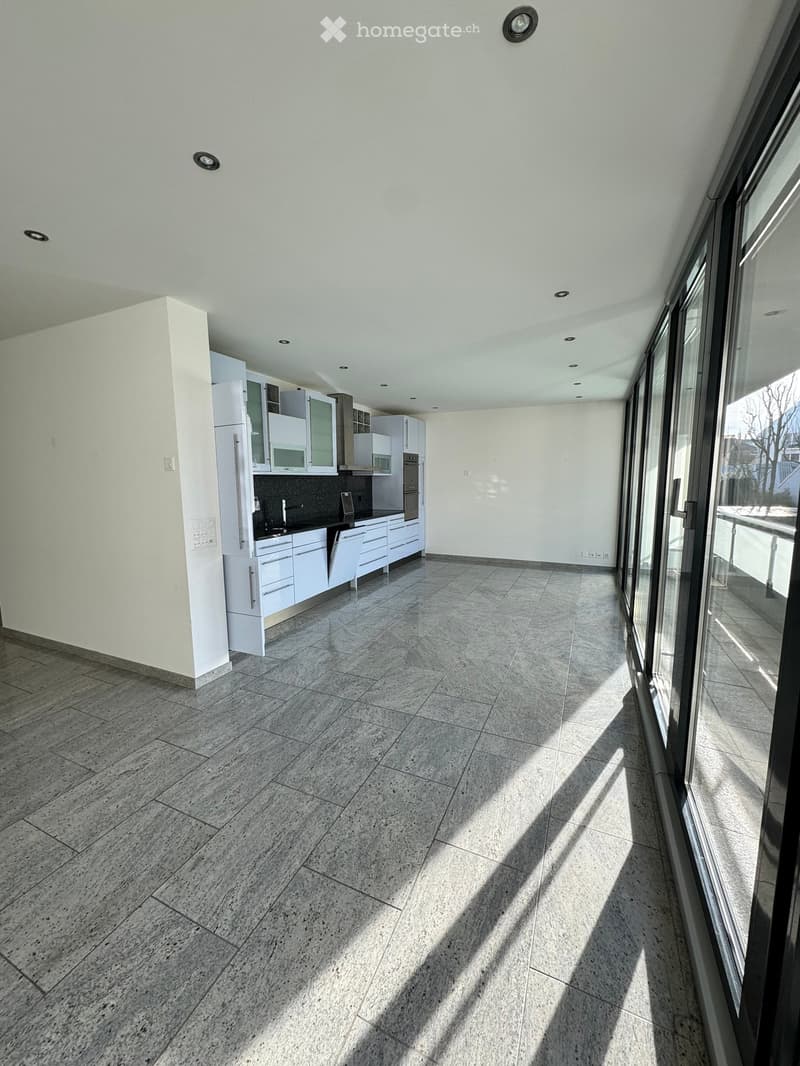 Modern kitchen with white cabinets, stainless steel appliances, and large windows allowing natural light to fill the space.