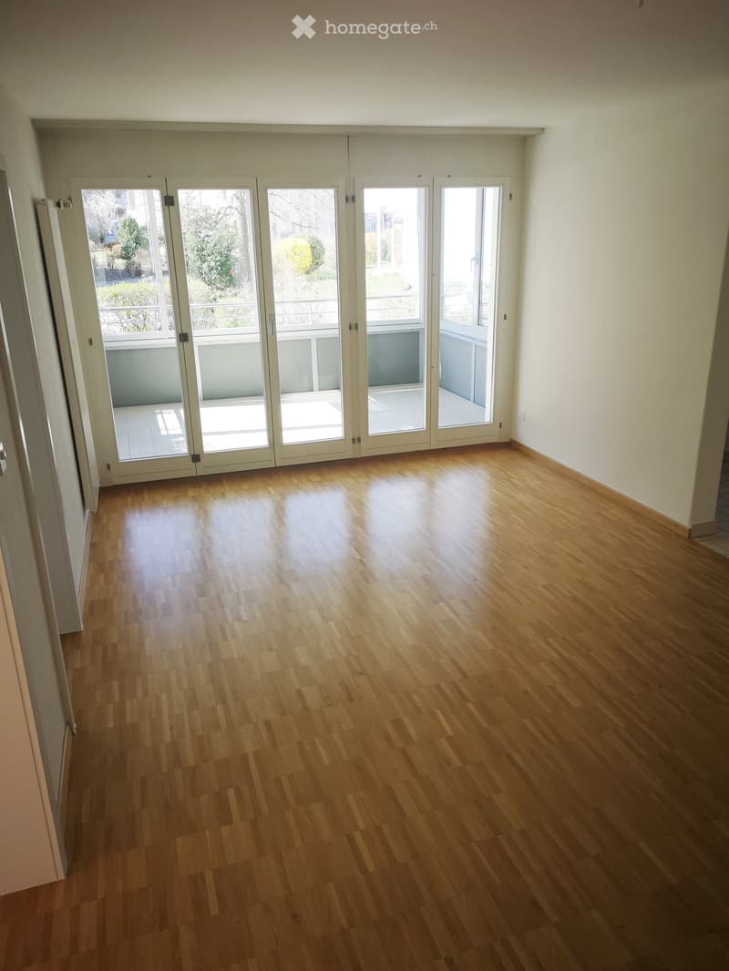 Empty room, hardwood floors, sliding doors, balcony with a railing, white walls