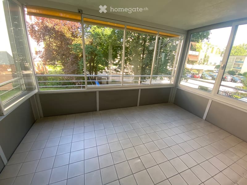 spacious balcony, tile flooring, large windows, metal railing, exterior view of trees and buildings