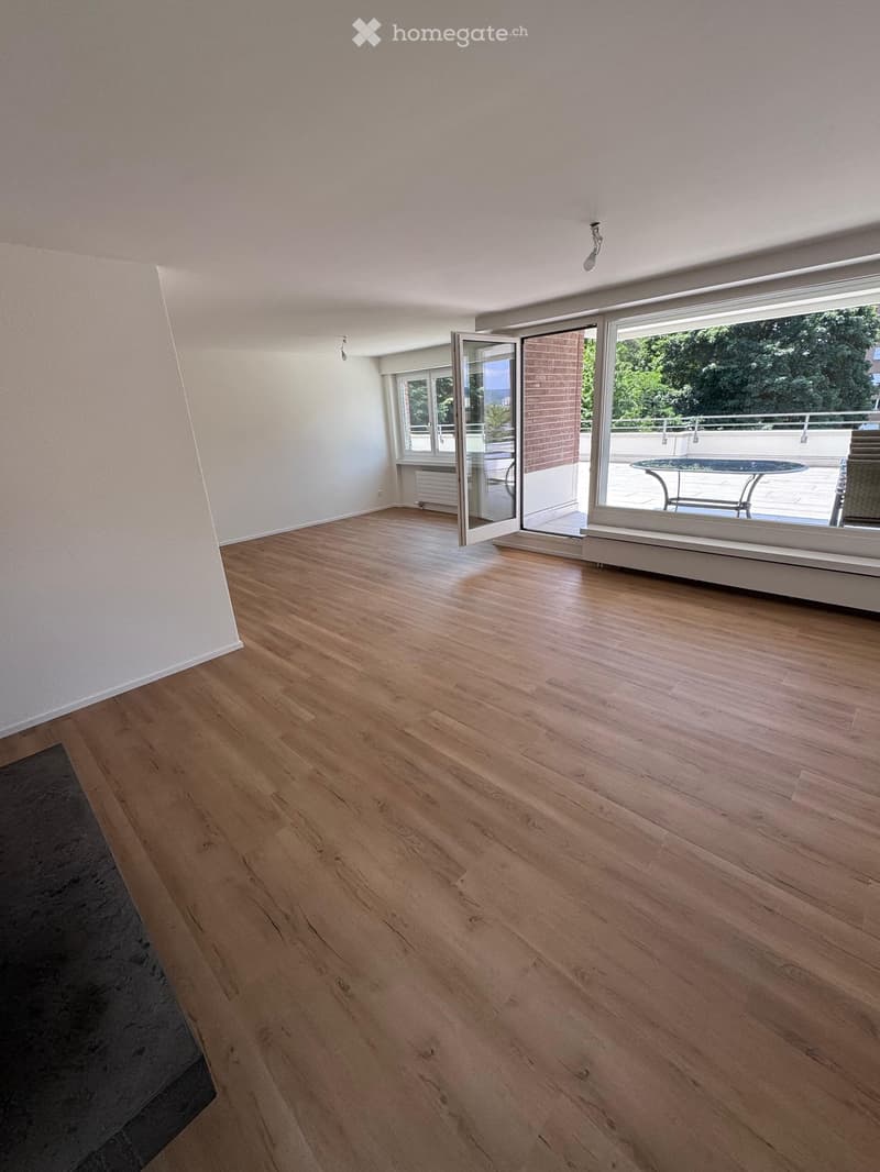 Empty room with light wooden flooring, white walls, and large sliding glass doors leading to a balcony.