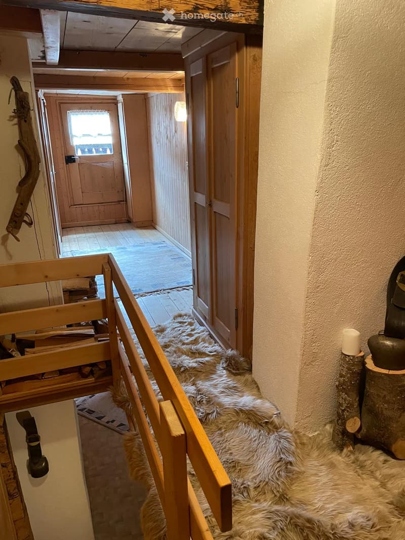 Wooden staircase with fur rugs, wooden railings, and a small open doorway leading to another room.
