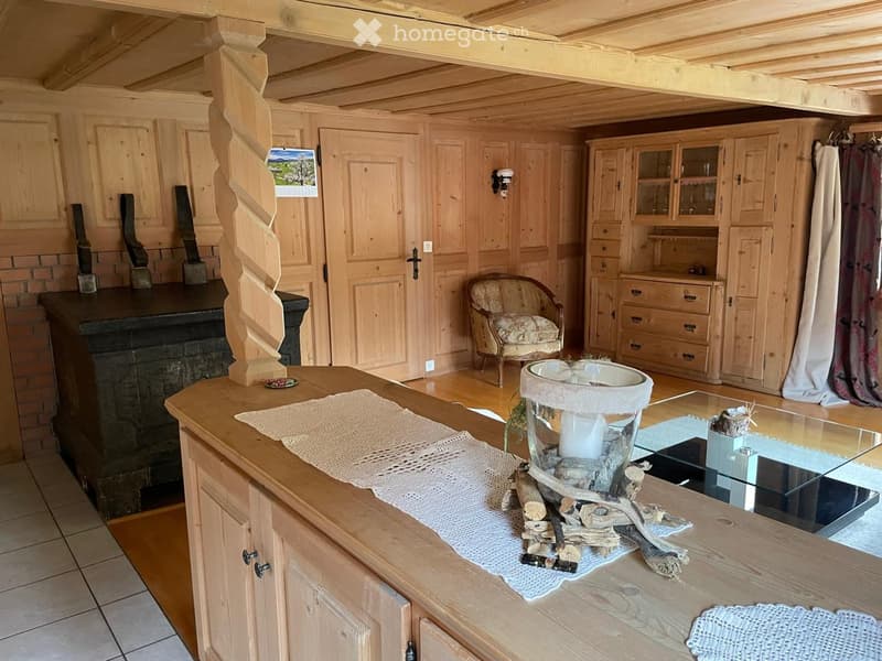 A cozy wooden interior with a fireplace, a wooden table with a decorative centerpiece, a chair, and wooden cabinets.