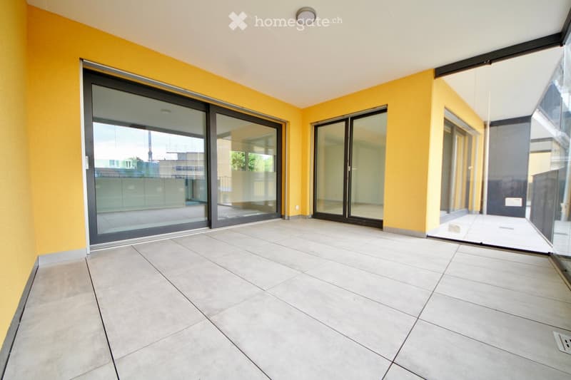 Empty balcony with large sliding glass doors, beige tiled floor, and yellow walls.