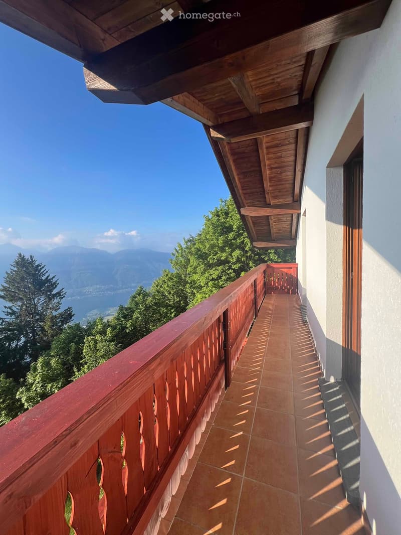 Balcony with wooden railing, tiled floor, and scenic mountain view.