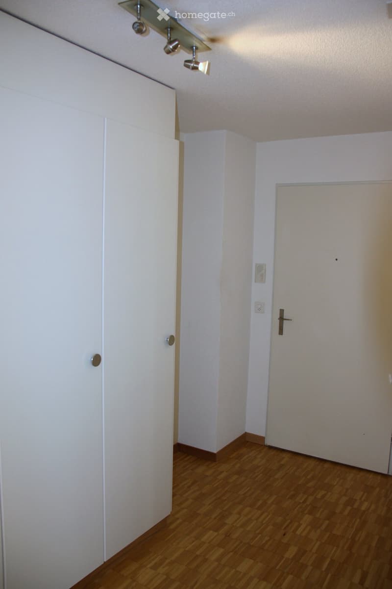 Empty room with wooden flooring, white walls, and two white doors.