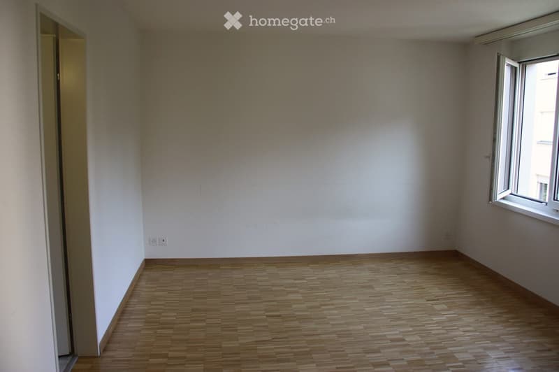 Empty room with wooden flooring, white walls, and a window with white frame. No furniture or equipment visible.