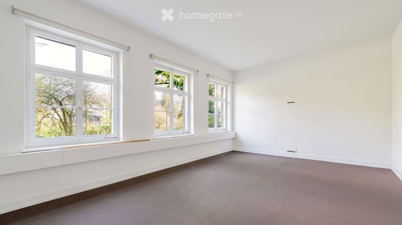 Empty room with white walls, large windows, and carpeted floor. No furniture or equipment present.