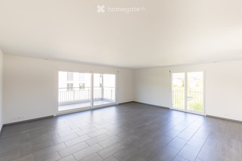 Empty room with white walls, grey tiled floor, and large sliding glass doors leading to a balcony.