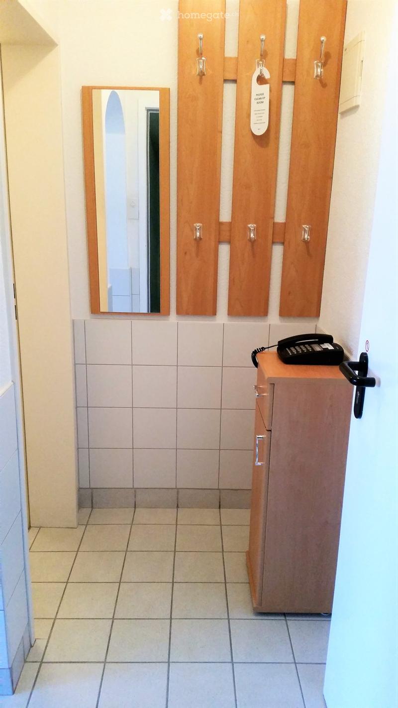 empty room, white tiles, wooden cabinet, mirror, telephone, hooks