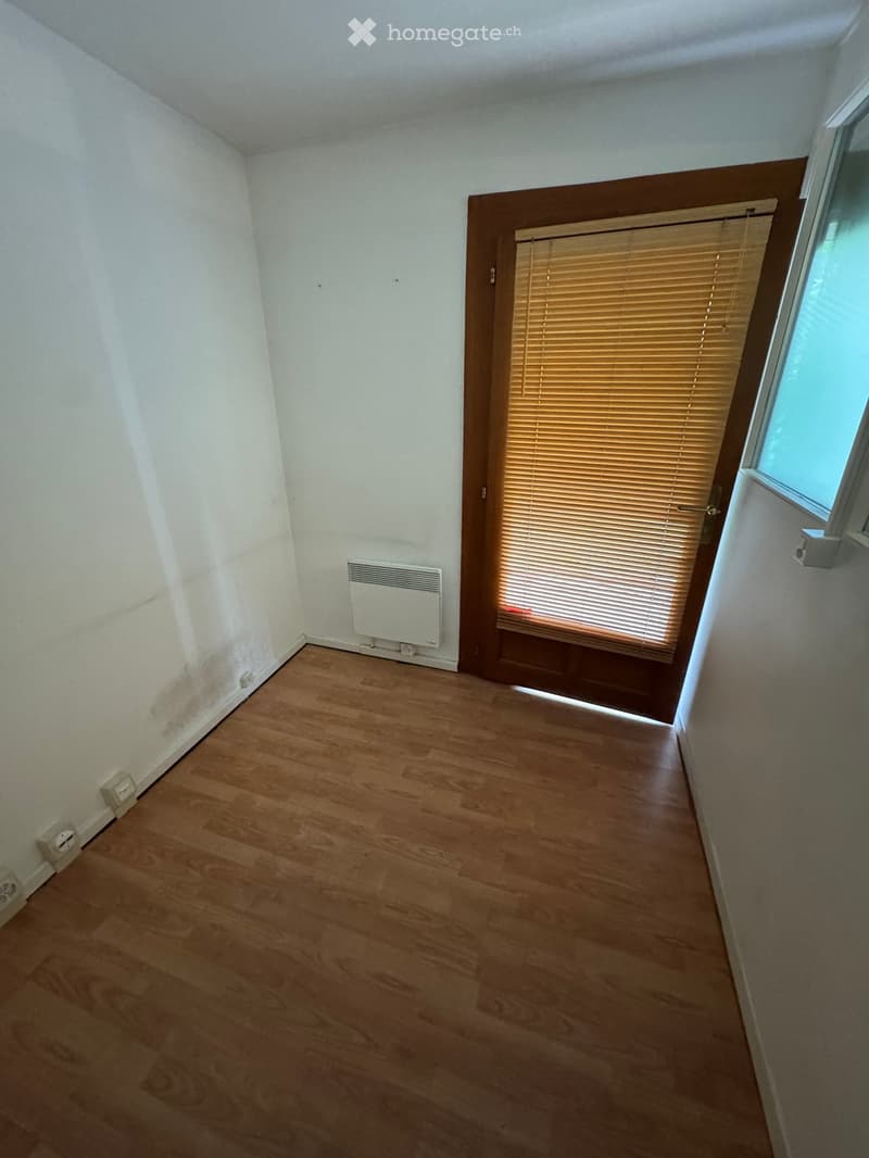 Empty room with wooden flooring, white walls, a radiator, and a window with blinds.