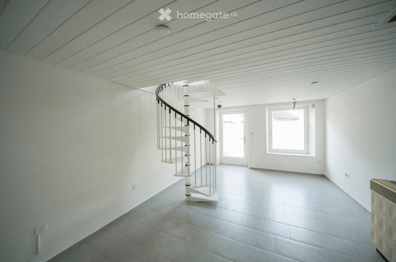 Modern, minimalist hallway with a white spiral staircase, large windows, and neutral-colored walls and flooring.
