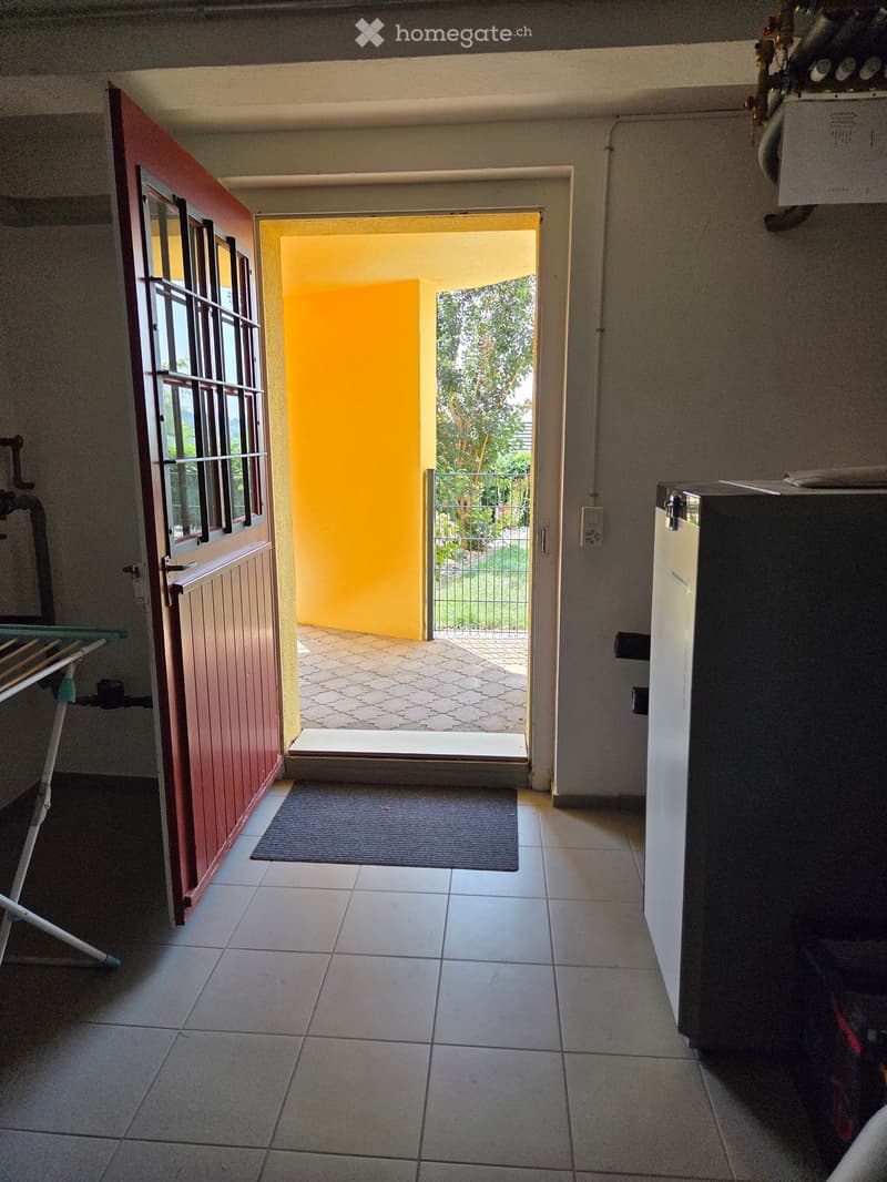 Hallway with tiled floor, open door leading to a patio area, small rug, and a folding table on the left side.