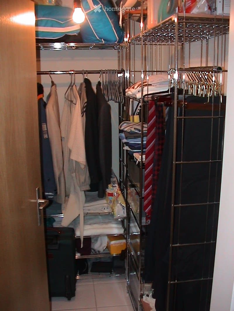 A well-organized closet with multiple clothing racks, neatly hung garments, folded towels, and various storage items.