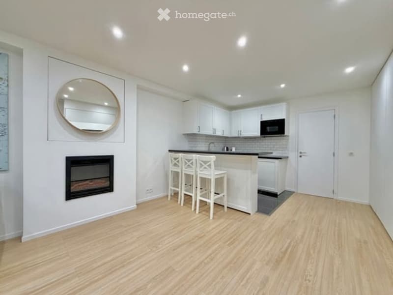 Modern kitchen with white cabinets, a central island with bar stools, a built-in microwave, and a fireplace on one wall.