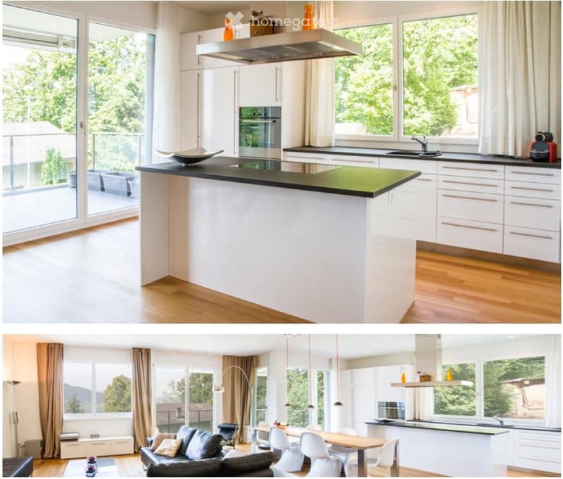 Modern kitchen with white cabinets, black countertop island, stainless steel appliances, large windows with a view of greenery, and a coffee maker on the counter.