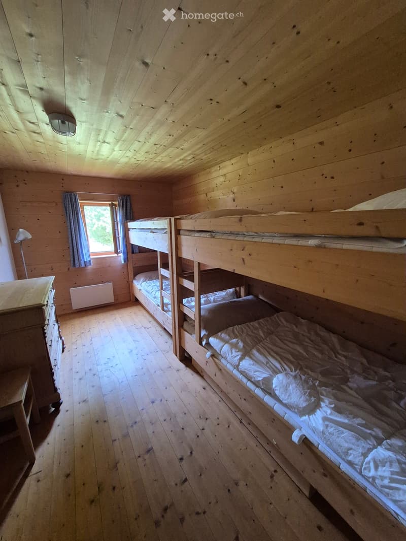 Cozy wooden bedroom with bunk beds, wooden floor, and a window with curtains.