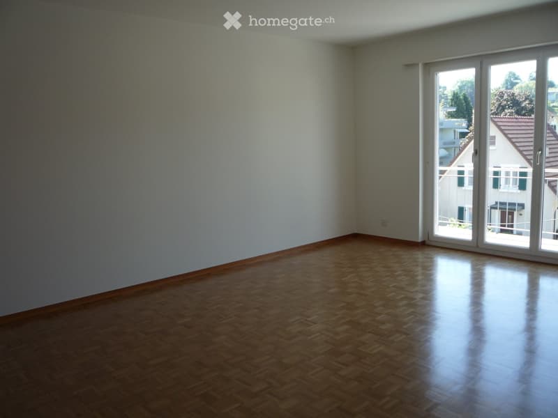 Empty room with wooden flooring and large sliding glass doors leading to a balcony.